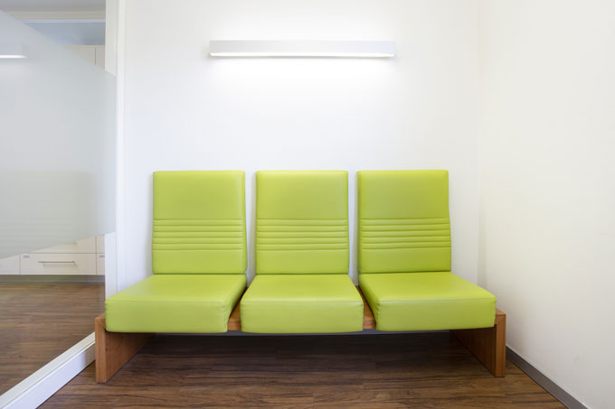 Wartebereich der Zahnarzt-Praxis mit grünen Leder-Sitzen